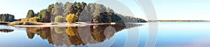 Panoramic view of the forest island, pond or lake. The reflection in the water. Beautiful widescreen autumn landscape.