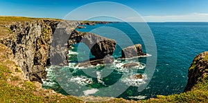 A panoramic view of the Green Bridge of Wales standing proud in the early summer sunshine on the Pembrokeshire coast, Wales