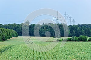 Panoramic view of a green field and high voltage towers, electricity pylons in the distant