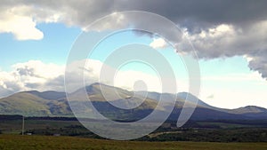 Panoramic view of green hills under a partly cloudy sky on the Isle of Skye, Scotland