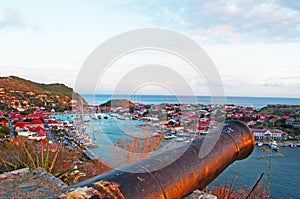 Panoramic view of Gustavia harbour at sunset, old cannon, hill, St Barth, sailboats