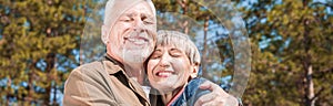 panoramic view of happy senior couple embracing with smile and closed eyes.