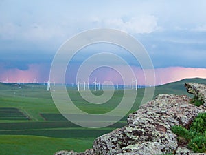 A panoramic view on a hilly landscape of Xilinhot in Inner Mongolia. Endless grassland with a few wind turbines in the back