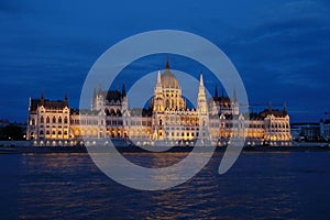 Panoramic view of the Hungarian parliament with illumination of walls from Danube at night.