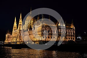 Panoramic view of the Hungarian parliament with illumination of walls from Danube at night.