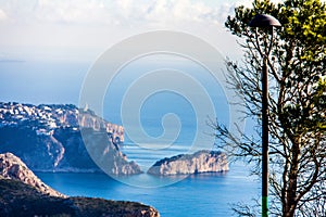 Panoramic view of La Nao cape in Javea, Spain. A tree and a streetlamp in the foreground. photo