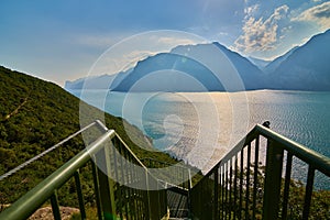 Panoramic view on Lake Garda from the Busatte-Tempesta trail near Nago-Torbole with the iron staircase,  Torbole  town surrounded