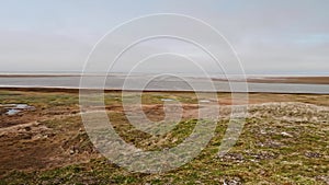 Panoramic view of landswell of Yamal peninsula and Kara sea. Flock of geese flying in the sky over water.