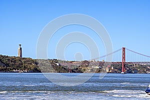 Panoramic view of Lisbon\'s April 25 steel suspension bridge and the religious monument.