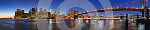 Panoramic view of Lower Manhattan Financial District skyscrapers at twilight with the Brooklyn Bridge and the East River. New York