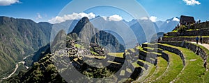 Panoramic view of Machu Picchu ruins in Peru. Behind we can appreciate big and beautiful mountains full of green vegetation.