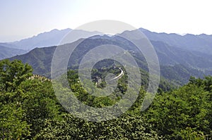 Panoramic view from the majestic Great Wall of China to the surrounding green landscape and dark forests. The moutains
