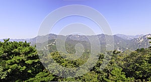 Panoramic view from the majestic Great Wall of China to the surrounding landscape and forests. The horizon is in the