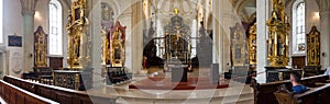 Panoramic view of the man sits inside the gorgeous church. Golden interior with wooden ornaments