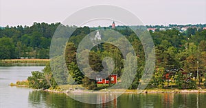 Panoramic View On Many Red Swedish Wooden Sauna Logs Cabins Houses On Island Coast In Summer Cloudy Day. Swedish Old