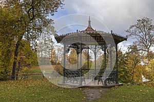 Panoramic view of metal openwork gazebo in public park in autumn