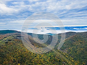 Panoramic view of the mountains covered with forests in the autumn aura. Autumn over the mountains with a thick morning fog