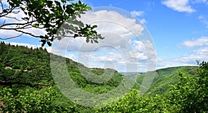Panoramic view of mountains covered with greenery under a cloudy blue sky in Ehrenburg, Germany photo