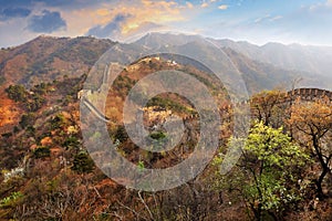 Panoramic view of the Mutianyu section of the Great Wall of China, surrounded by green and yellow vegetation under a