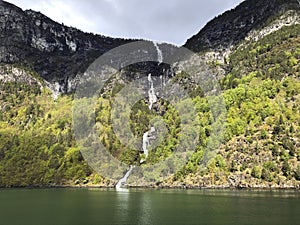 Panoramic view of Naeroyfjord with a tall waterfall in Scandinavian mountains