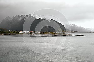 Panoramic view of the norwegian coast and a village in front of a snowcapped mountain range during winter on Lofoten Islands in No