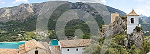 Panoramic view of the old bell tower of Guadalest with the Serrella mountain range in the background and the Guadalest reservoir