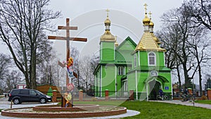 Panoramic view of orthodox wooden green church with golden domes and big wooden cross. Religion and Easter concept