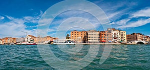 Panoramic view over busy Grand Canal, piers, promenade embankment and colorful buildings in Venice, Italy