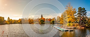 Panoramic view over city park Rotehorn and lake with tour boats in Autumn colors at sunny day with blue sky at sunset, Magdeburg,