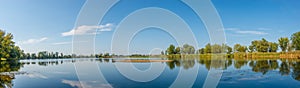 Panoramic view over a lake near Elbe river with wind turbines at sunny day and blue sky, Magdeburg, Germany