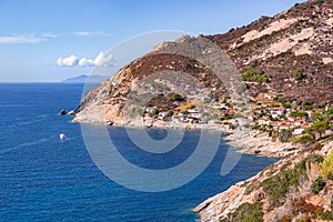 Panoramic view over rocky beach of little village Chiessi and coastal road in autumn at western Elba Island, Italy