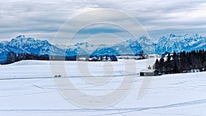 Panoramic view over snowy pre-alpine landscape with two riders on horses photo