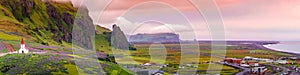 Panoramic view over sunset at black sand beach, small city Vik and violet lupine flowers and lonely church, South Iceland, summer