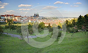 A panoramic view of Prague City under blue sunny sky with Prague Castle and St. Vitus Cathedral on the left