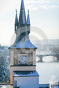 Panoramic view of Prague red tiled roofs with snow at sunny winter day, view from Bridge Tower to Old town water tower with clock