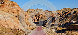 Panoramic view of a red cobblestone road leading towards the Rainbow Mountains.
