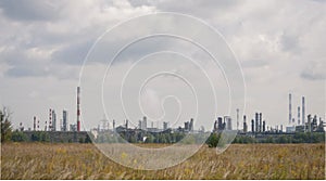Panoramic  view of the refinery with high striped pipes and yellow autumn field