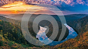 Panoramic view of river canyon with dark water and autumn colorful forest. Horseshoe bend, Vltava river, Czech republic.