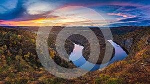 Panoramic view of river canyon with dark water and autumn colorful forest. Horseshoe bend, Vltava river, Czech republic.