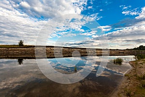 Panoramic view of riverbank with reflections of white fluffy clo photo