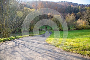 Panoramic view on a road with green meadows blue sky, in autumn with forest