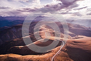 Panoramic view of the road winding along the mountain plateau. Autumn. Cloudy day. Shooting from a drone.