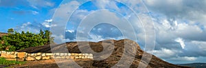 A panoramic view of rock formation with blue and dramatic sky at Chitharal Malai kovil