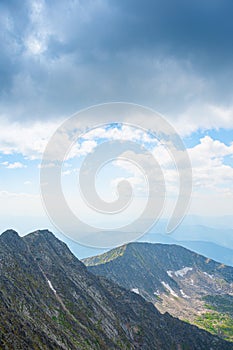 Panoramic view of rocky ridge. Mountains on horizon under cloudy sky. Travel through mountain valley