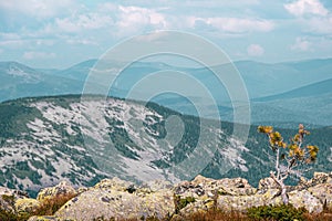 Mountains on horizon under cloudy sky. Travel through mountain valley on sunny day