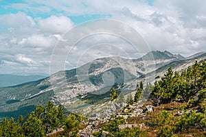 Panoramic view of rocky ridge. Mountains on horizon under cloudy sky. Travel through mountain valley