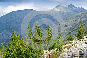 Panoramic view of rocky ridge. Mountains on horizon under cloudy sky. Travel through mountain valley