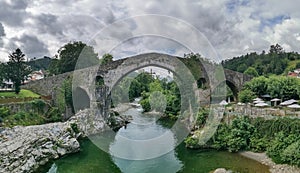 Panoramic view at the Roman bridge over Sella river, an iconic bridge on Cangas de OniÂ­s downtown city, Picos de Europa or Peaks photo