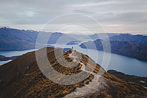 Panoramic view of the Roys Peak in New Zealand with mountains in distance under a light cloudscape