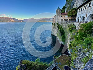 Panoramic View of Santa Caterina del Sasso Hermitage on the Cliffside Overlooking the Tranquil Waters of Lake Maggiore photo